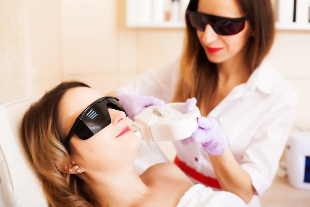 Mulher fazendo depilação a laser no estúdio de beleza.