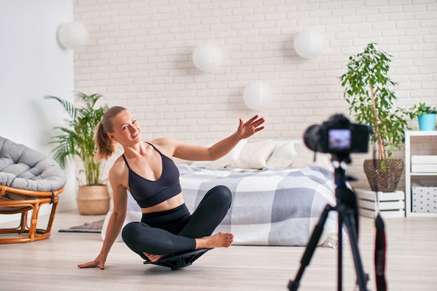 Mulher fazendo exercício em um equilibrador de simulador especial. sportswear atlético loiro, o exercício em casa fortalece os músculos.