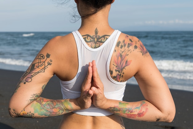 Foto mulher fazendo exercícios de ioga em uma praia preta