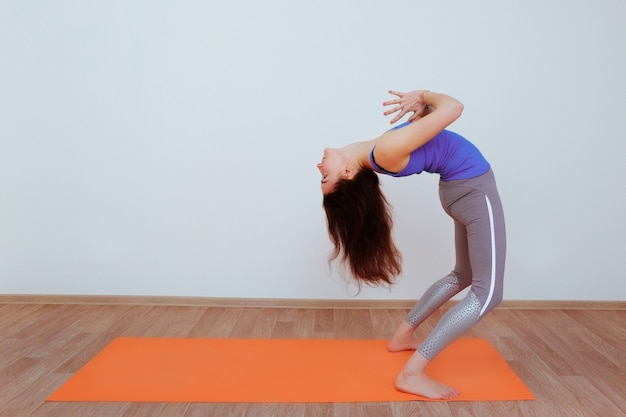 Mulher fazendo exercícios de ioga na esteira laranja, alongamento.