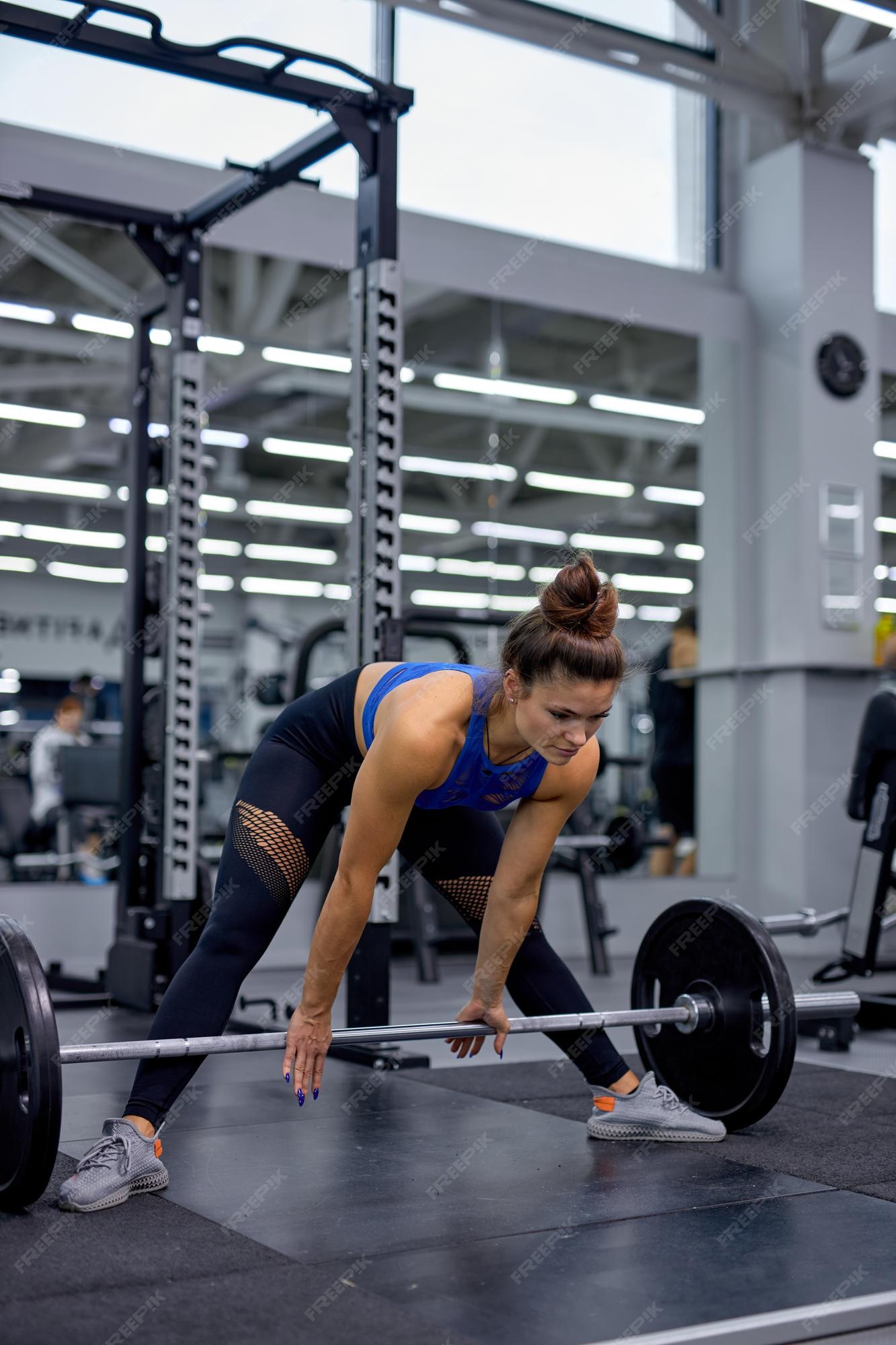 Mulher fazendo levantamento terra com um barbell isolado no fundo branco