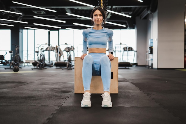 Mulher fazendo exercícios de tríceps em uma caixa de salto de madeira crossfit