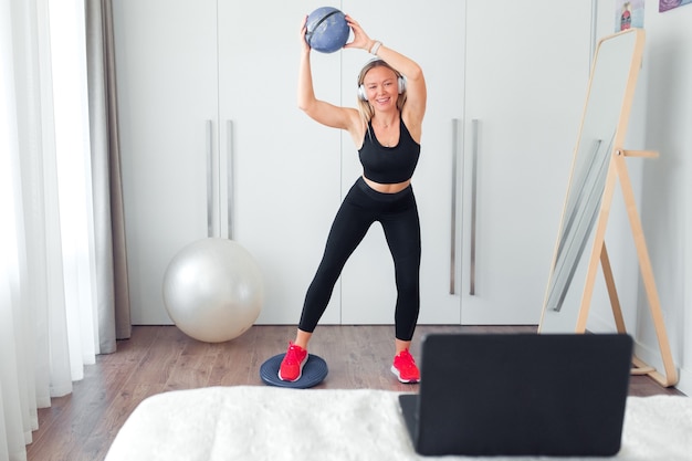 mulher fazendo exercícios físicos em casa usando a bola