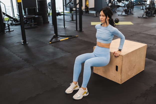 Mulher fazendo flexão reversa no tríceps em uma caixa de crossfit na academia