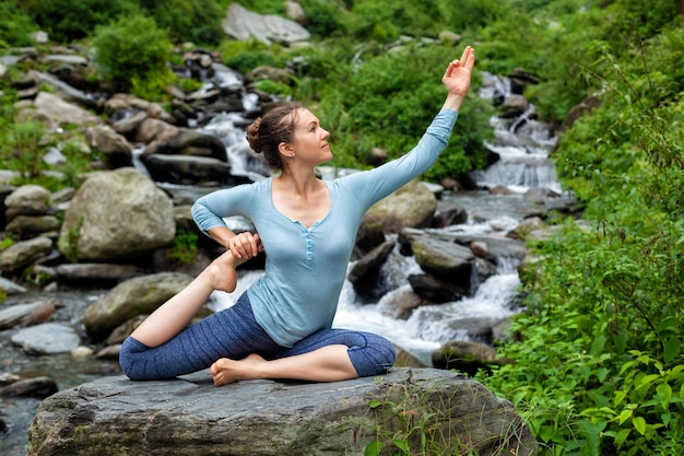 Mulher fazendo ioga asana em cachoeira tropical