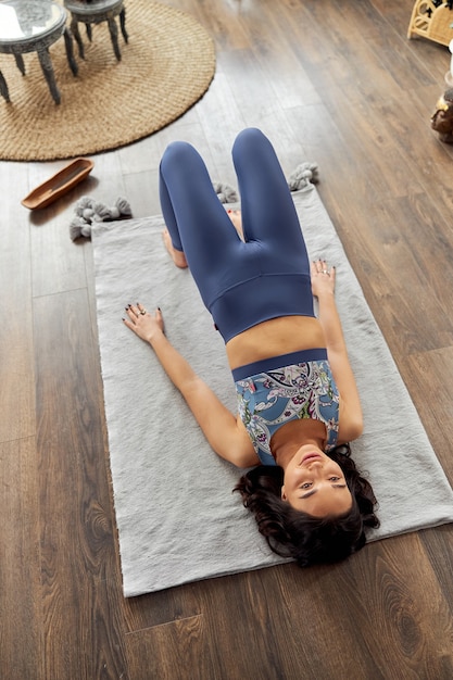 Mulher fazendo ioga e praticando meditação em um quarto decorado em estilo bali