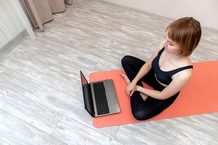 Mulher fazendo ioga em casa com laptop
