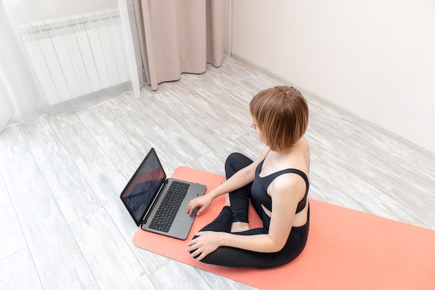 mulher fazendo ioga em casa com laptop