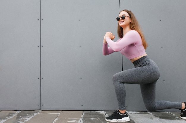 mulher fazendo lunges exercícios no fundo da parede