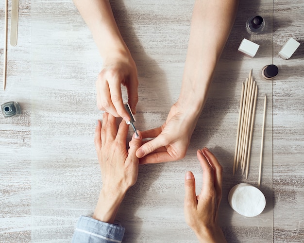 Mulher fazendo manicure para um cliente dentro de casa