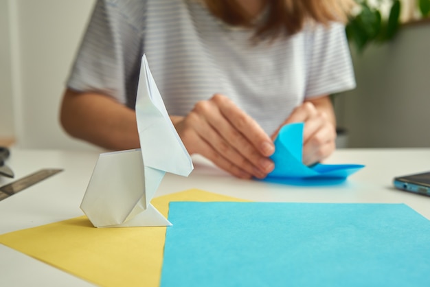 Mulher fazendo origami de coelho da páscoa de papel colorido