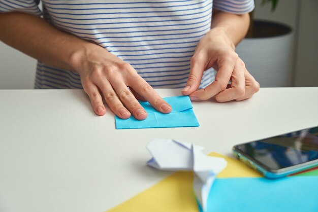 Mulher fazendo origami de coelho da páscoa de papel colorido