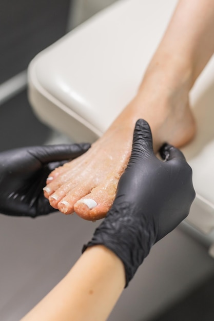 Foto mulher fazendo peeling de pés em um salão de pedicura, esfregando açúcar e relaxando o procedimento de beleza