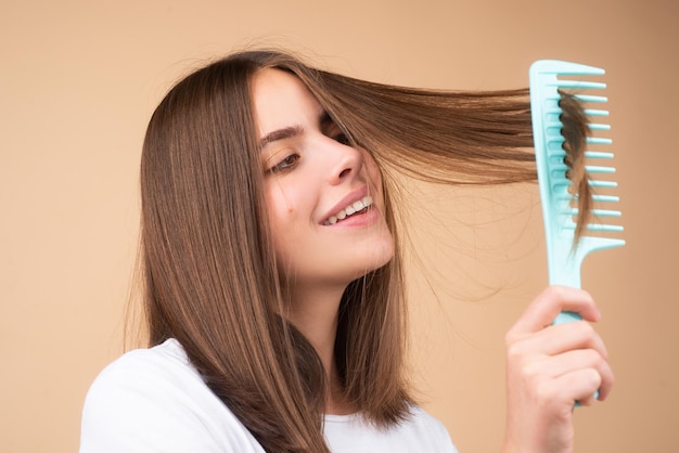 Mulher fazendo penteado com pente. Bela jovem segurando estúdio de cabelo saudável e brilhante