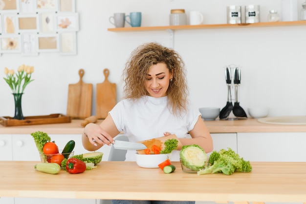 Mulher fazendo salada na cozinha.