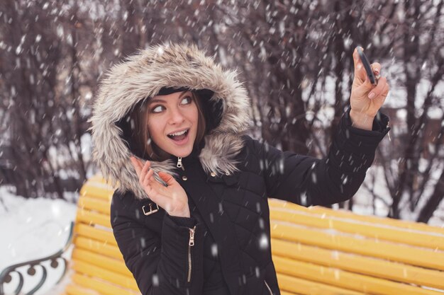 Mulher fazendo sua selfie em winter park sob flocos de neve