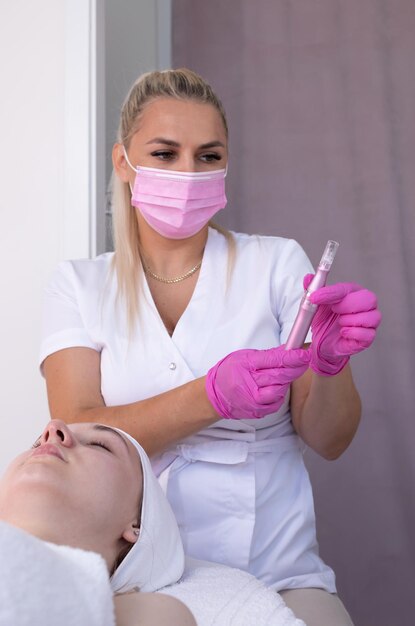 Foto mulher fazendo tratamento de microneedling mesoterapia cosmetologista feminina mantém microneidling elétrico