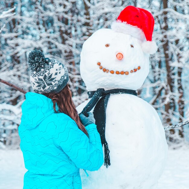 Mulher fazendo um boneco de neve no conceito de dia gelado de inverno