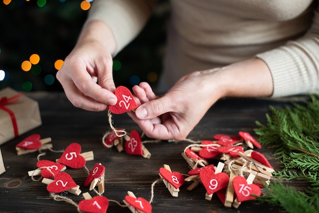 Mulher fazendo um calendário do advento para seu filho, preparação para o natal, férias diy crafting.