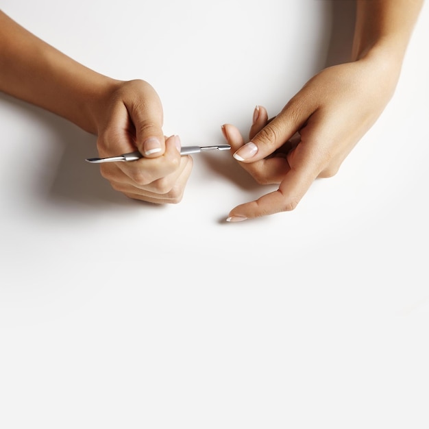 Foto mulher fazendo uma manicure com uma vara de metal para cutícula