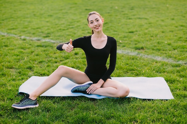 Mulher fazendo yoga gesticulando polegar para cima
