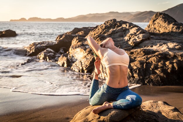 Mulher fazendo yoga na praia