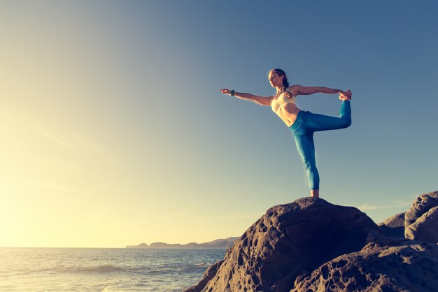 Mulher fazendo yoga na praia