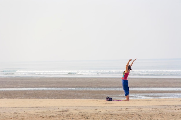 Mulher fazendo yoga na praia