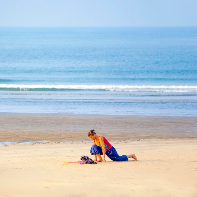 Mulher fazendo yoga na praia