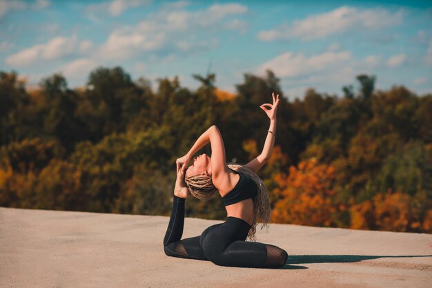 Mulher fazendo yoga no telhado de um arranha-céu na cidade grande.