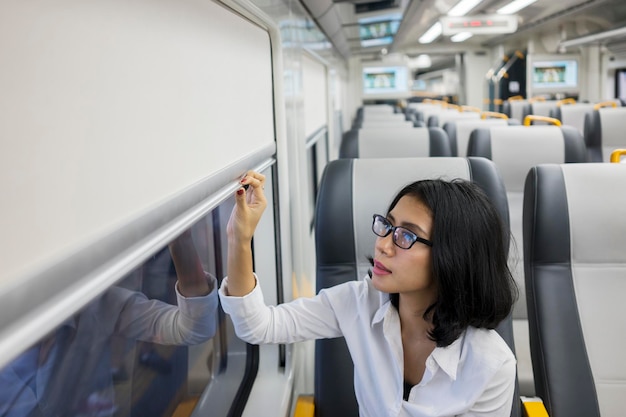 Mulher fechando a janela do trem com persianas