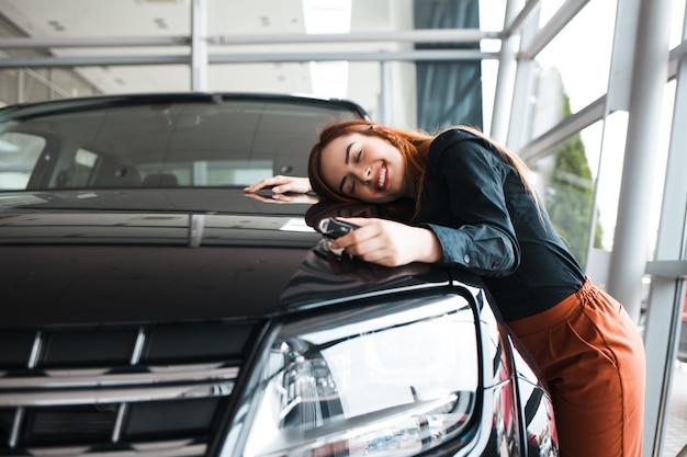 Foto mulher feliz abraça seu carro novo