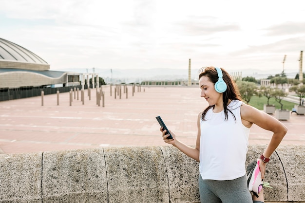 Mulher feliz alongando-se depois de correr usando o celular ao ar livre
