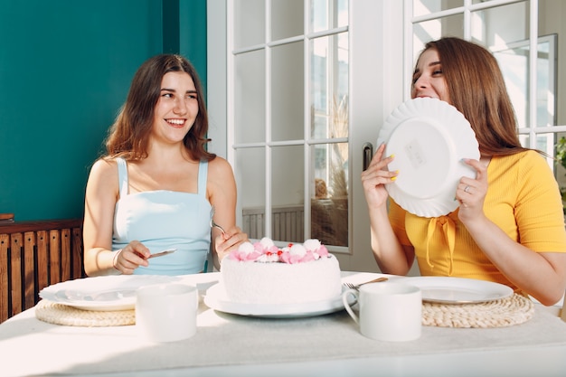 Mulher feliz amigos em casa sentado e sorrindo com bolo de aniversário branco.