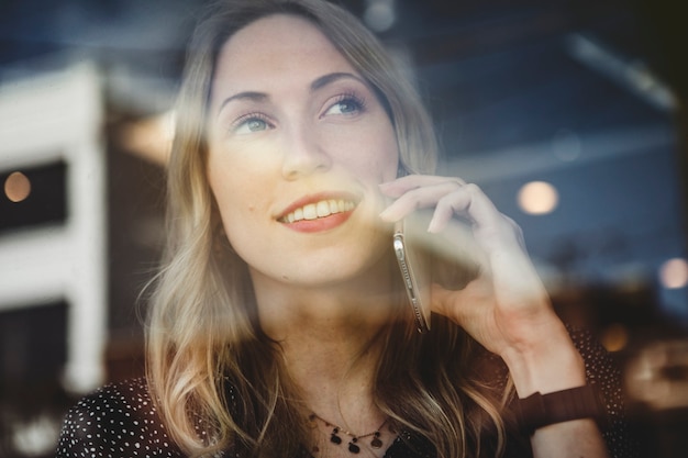 Mulher feliz ao telefone olhando pela janela