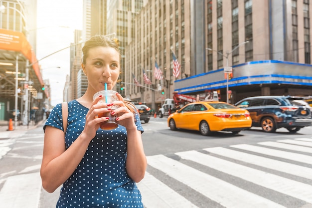 Mulher feliz bebendo café gelado em Nova York