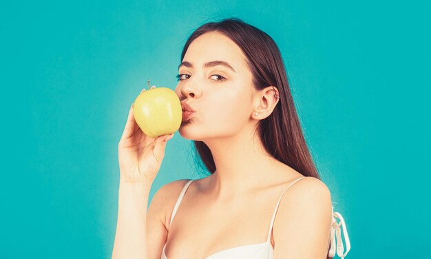 Mulher feliz beijo maçã sobre fundo azul. mulher saudável com maçã verde. mulher jovem e bonita comendo uma maçã. estilo de vida saudável.