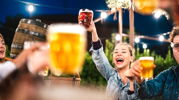 Mulher feliz brindando e torrando cerveja no pátio do bar do restaurante da cervejaria com amigos
