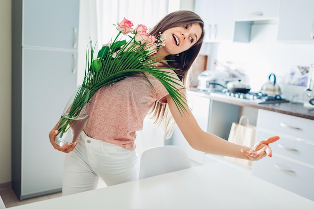 Mulher feliz coloca vaso com flores dançando e cantando garota cuida do aconchego na cozinha em qua