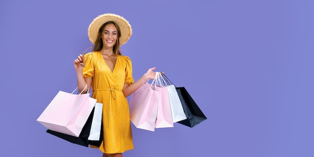 Mulher feliz com chapéu segurando óculos de sol e compras enquanto sorri para a câmera preta nas grandes vendas de sexta-feira