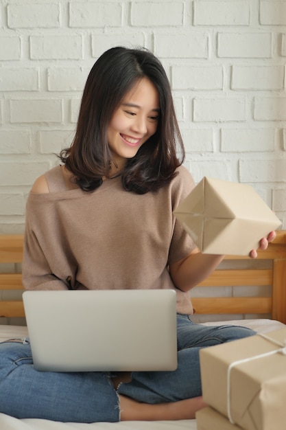 Mulher feliz com computador e caixa de pacote de produto em casa conceito de entrega de mercadoria em casa