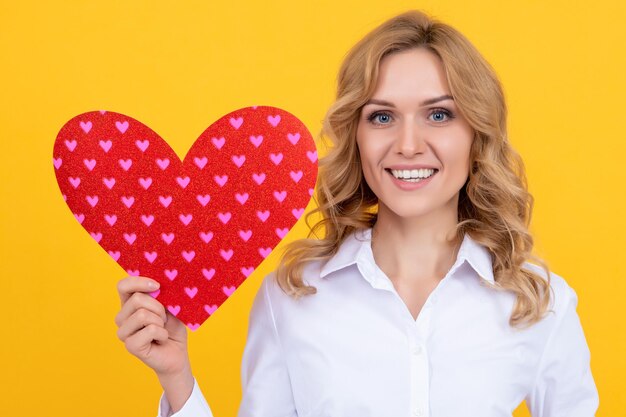 Mulher feliz com coração de amor vermelho na caridade de fundo amarelo