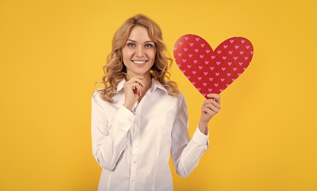 Mulher feliz com coração de amor vermelho sobre fundo amarelo dia dos namorados