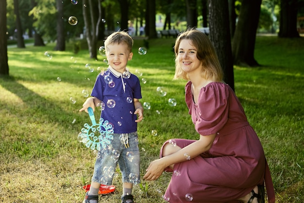 Mulher feliz com criança brinca com bolhas no parque