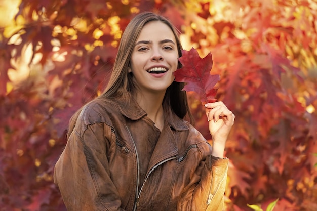 Mulher feliz com folhas coloridas de outono no retrato da árvore rowan