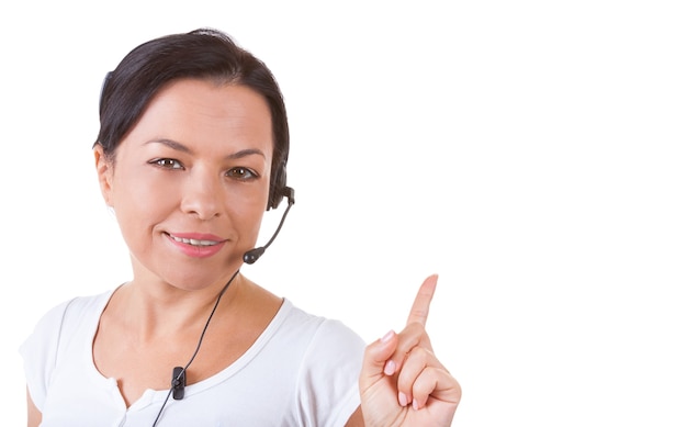 Mulher feliz com fone de ouvido trabalhando no callcenter mostra a direção do dedo para o copyspace para seu projeto em um fundo branco