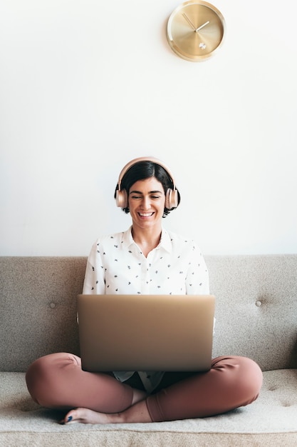 Mulher feliz com fones de ouvido no sofá