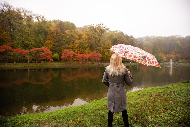 Mulher feliz com guarda-chuva no parque outono