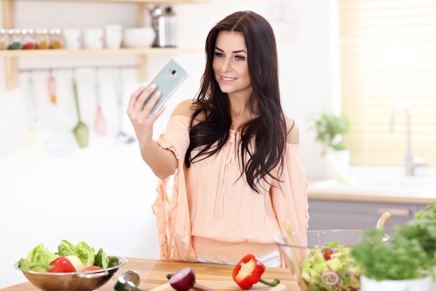 mulher feliz com legumes na cozinha moderna