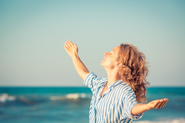 Mulher feliz com os braços abertos contra o fundo azul do mar e do céu